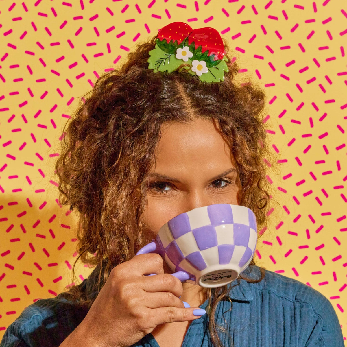 Woman drinking from a checkered mug with a colorful background