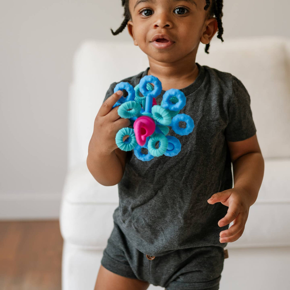 Child holding a blue and pink toy with a neutral background