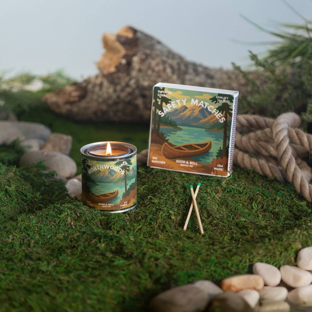 Candle and matches with nature-themed packaging on a mossy surface
