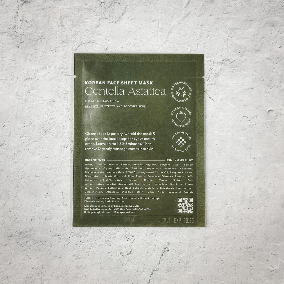 Korean face sheet mask packaging with green background on a textured gray surface