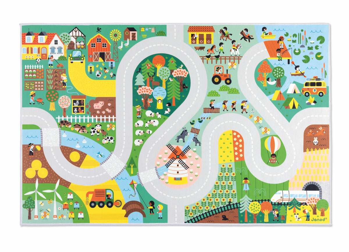 A colorful children's road-trip style play mat or puzzle board featuring illustrated farm, forest, and outdoor scenes connected by winding gray roads. The design includes houses, trees, animals, vehicles, fields, and small characters in many bright colors on a white border.