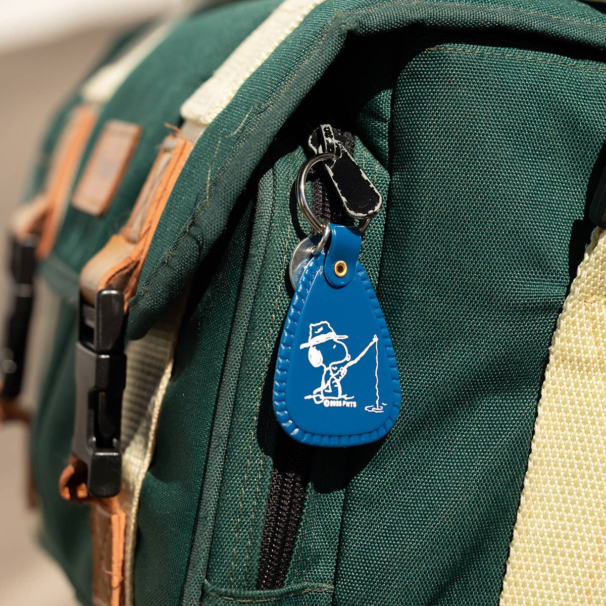 Blue keychain with a white design attached to a green bag