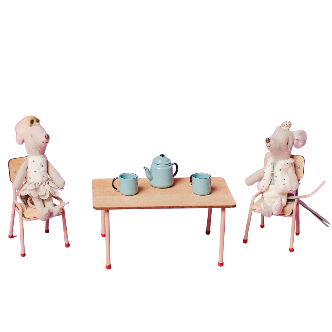 Two toy mice sitting at a small table with a teapot and cups on a white background