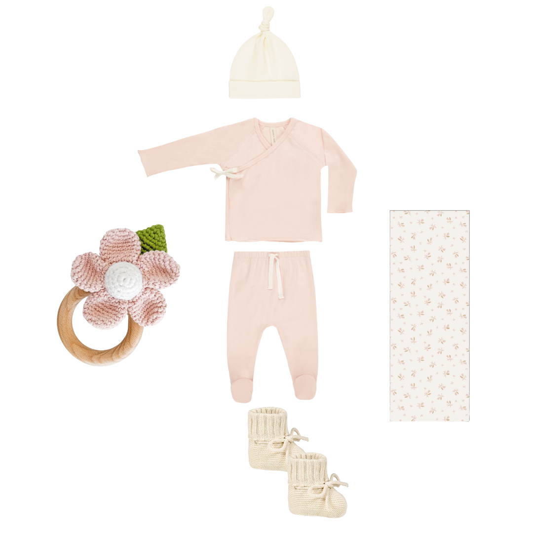 Collection of baby clothing and items including a onesie, hat, booties, and rattle on a white background.