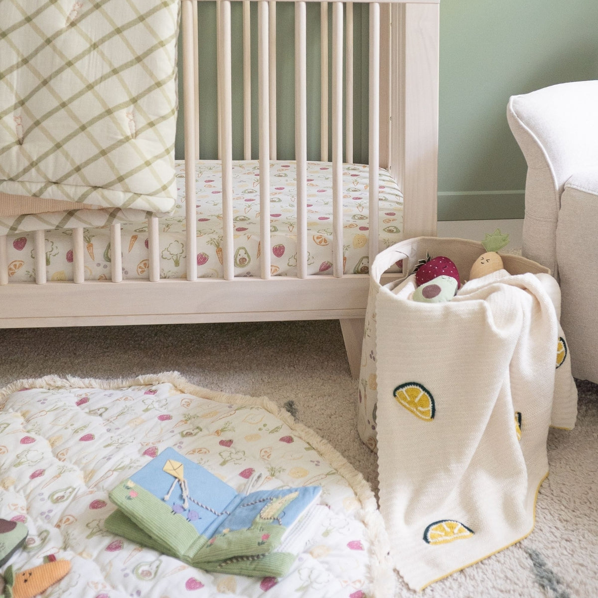 Nursery room with crib, toys, and a blanket on the floor.