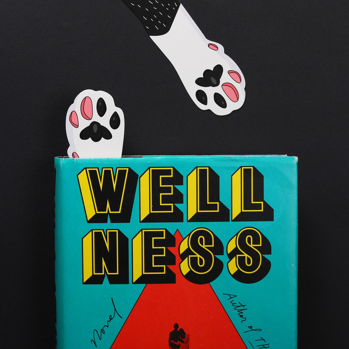 Book titled 'Wellness' with paw prints on a black background