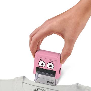 Pink cartoon-styled stamp being pressed onto a piece of paper with a hand holding it.