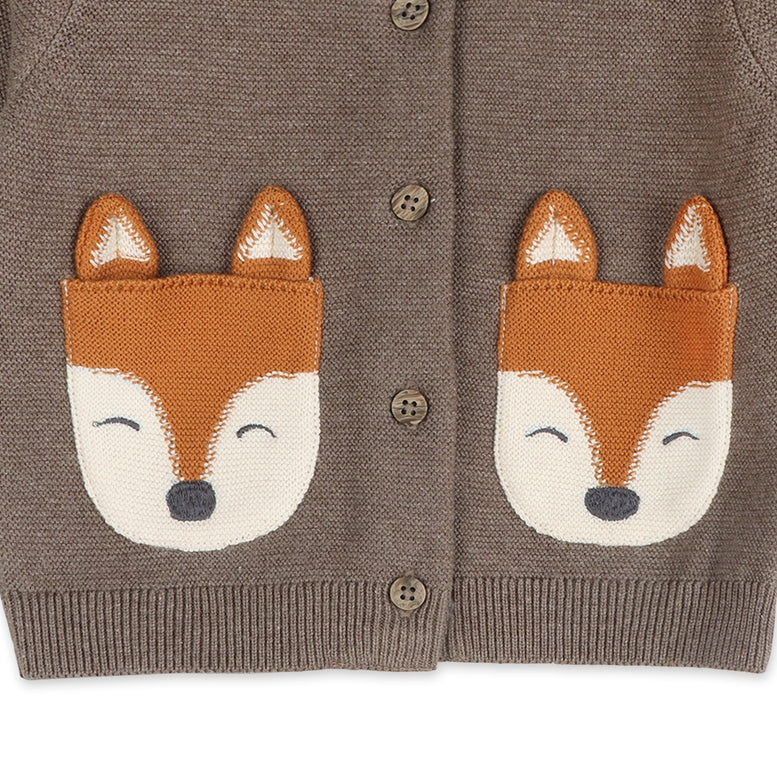 A close-up of a brown knit cardigan with two fox face patches on the chest and brown buttons, shown against a plain white background.