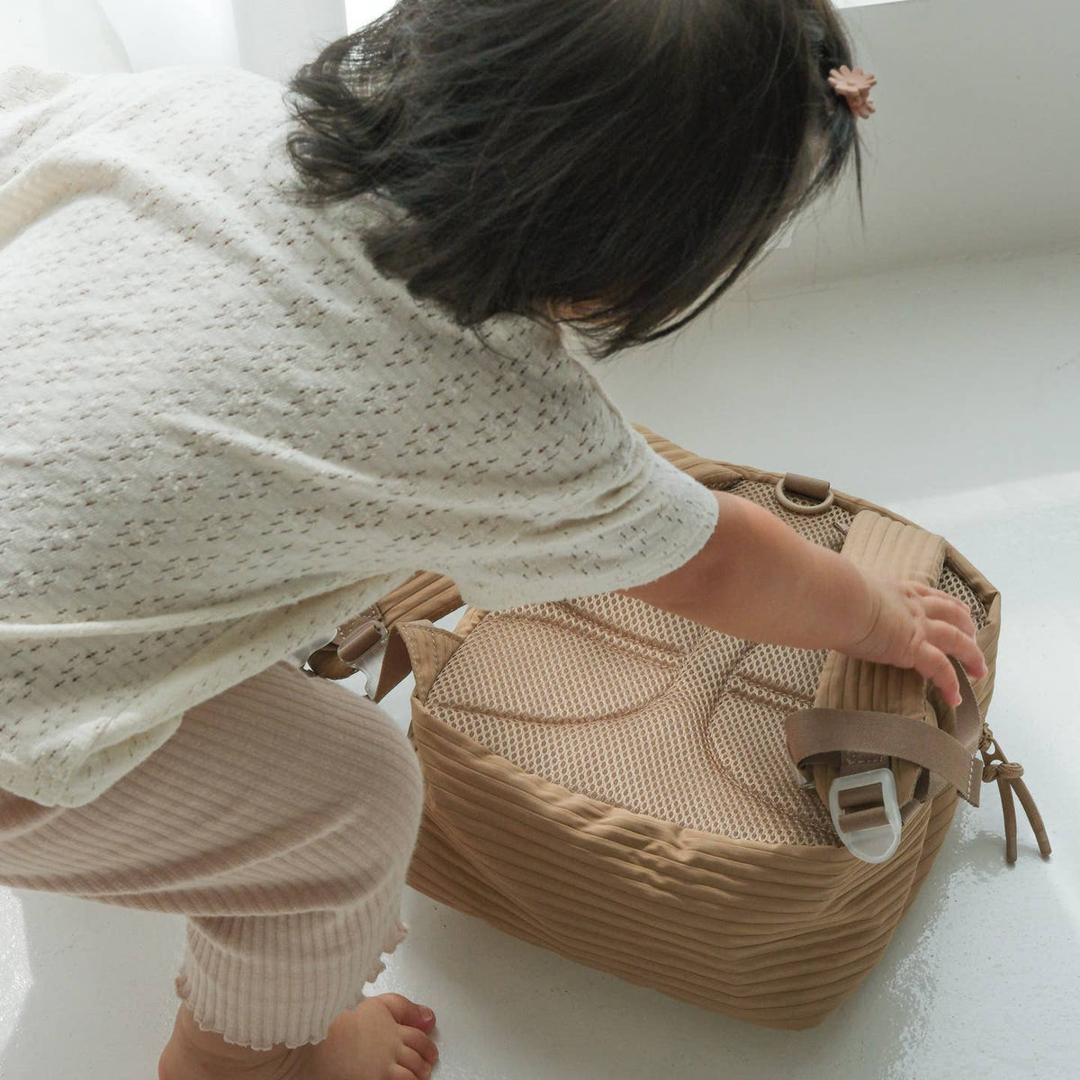 Child playing with a woven basket on a white floor