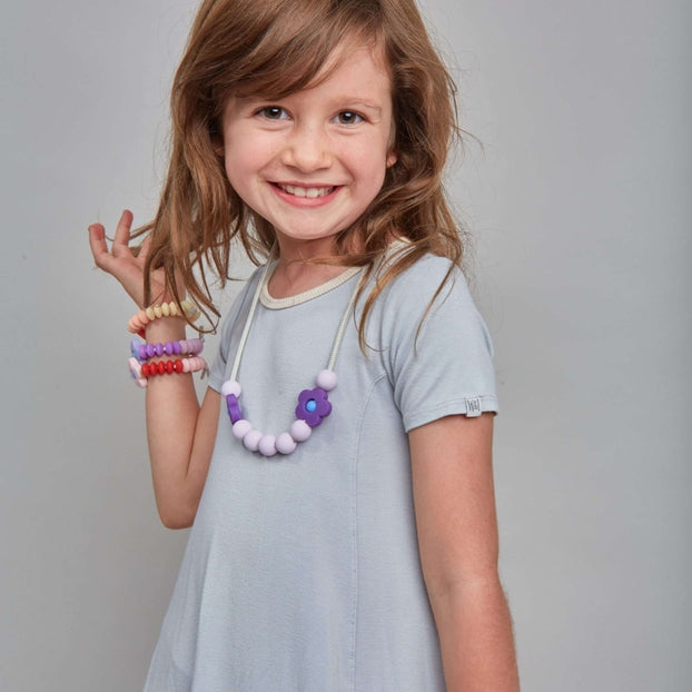 Young girl in a gray dress with jewelry on a gray background