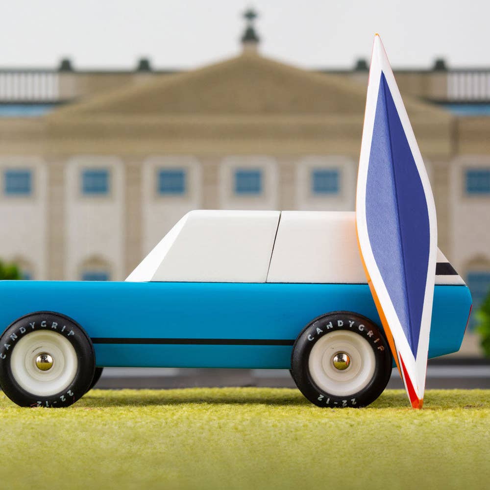 Model car with a sail on a grassy area in front of a building