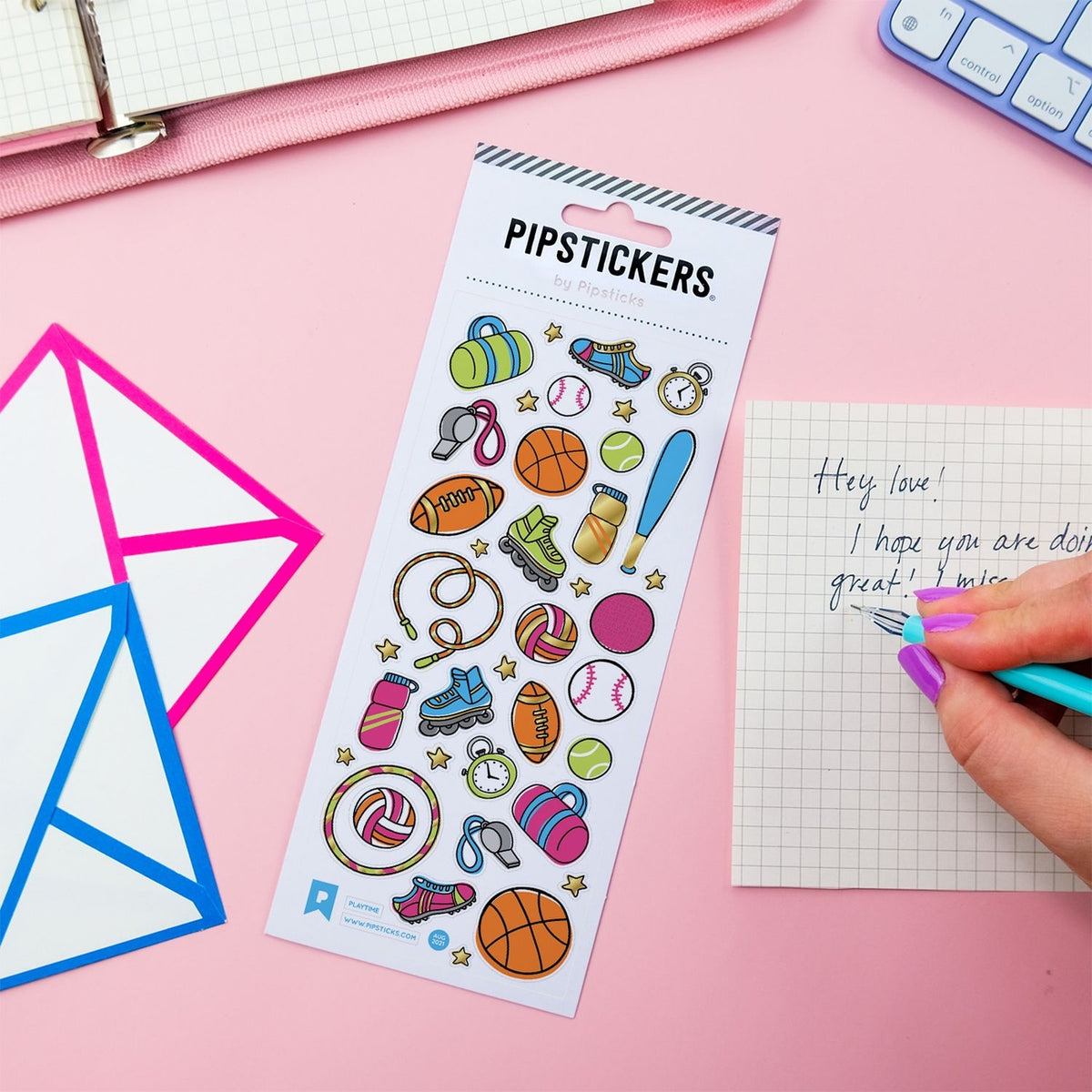 A sheet of colorful pip stickers labeled 'PIPPSTICKERS' is displayed on a pink desk. The sticker sheet contains various sports-themed illustrations like a basketball, baseball, bat, and sneakers.