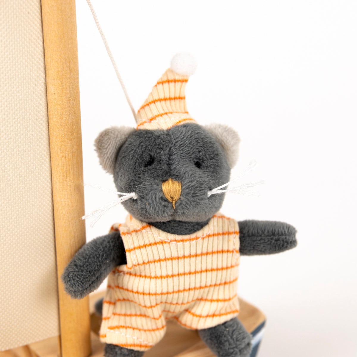 Plush toy cat in an orange outfit with a striped hat on a white background
