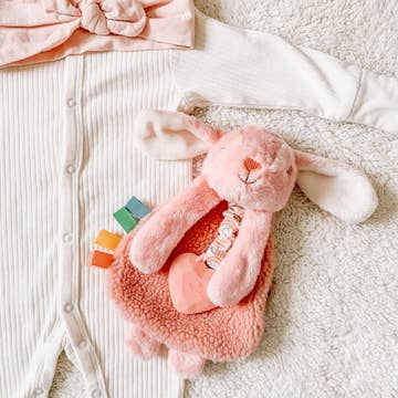 Pink plush toy with colorful teeth on a textured surface