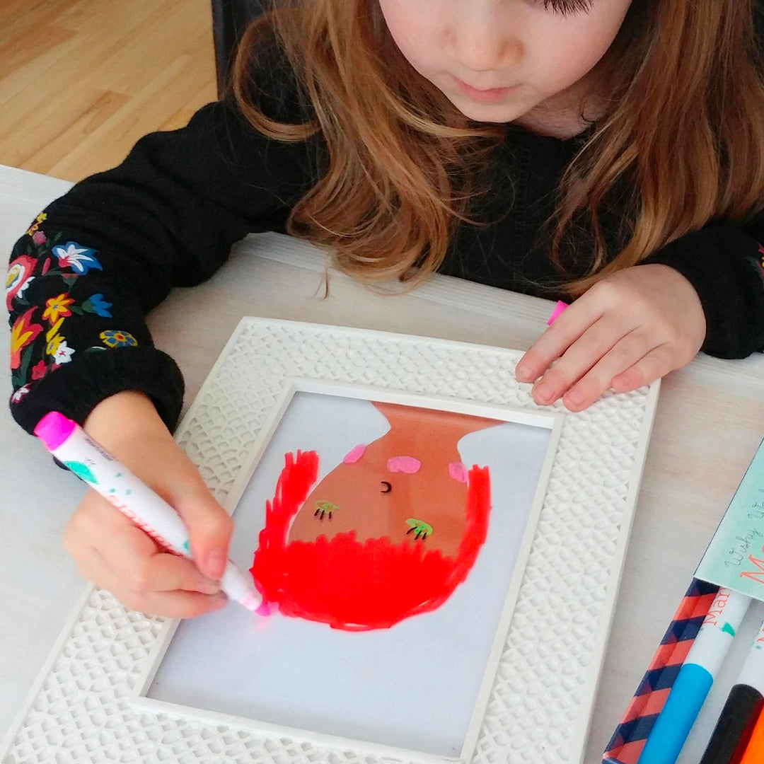 Child painting a picture of a fish with red paint on a white frame.