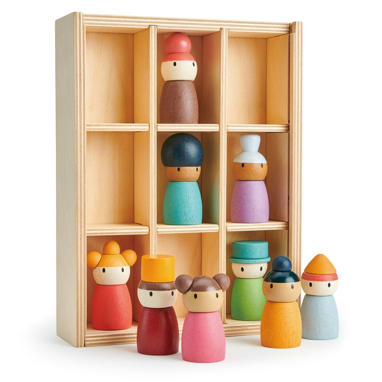 A wooden peg doll storage box with nine compartments, shown with several colorful wooden peg dolls arranged in front on a white background.