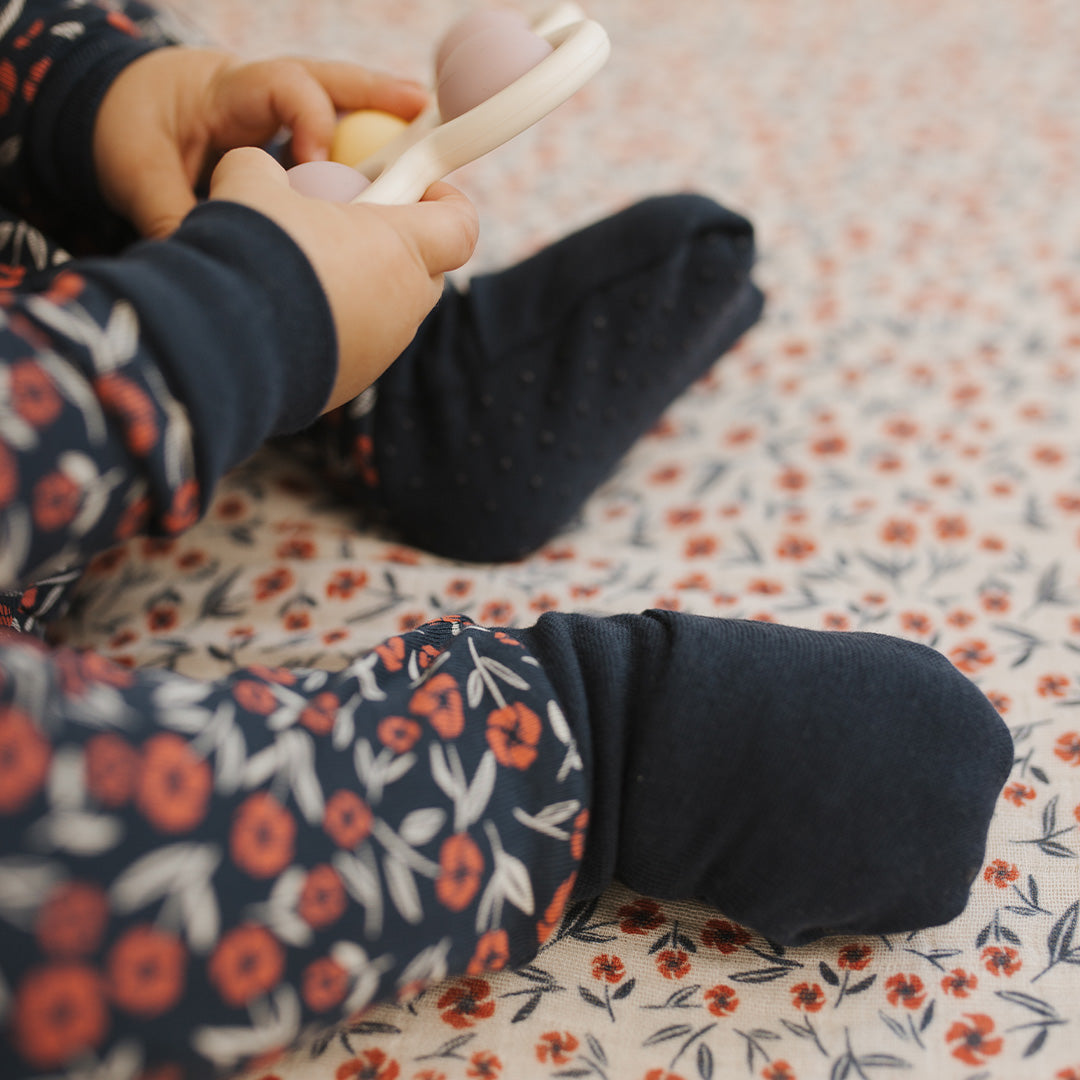 Child's legs in floral pants on a patterned floor