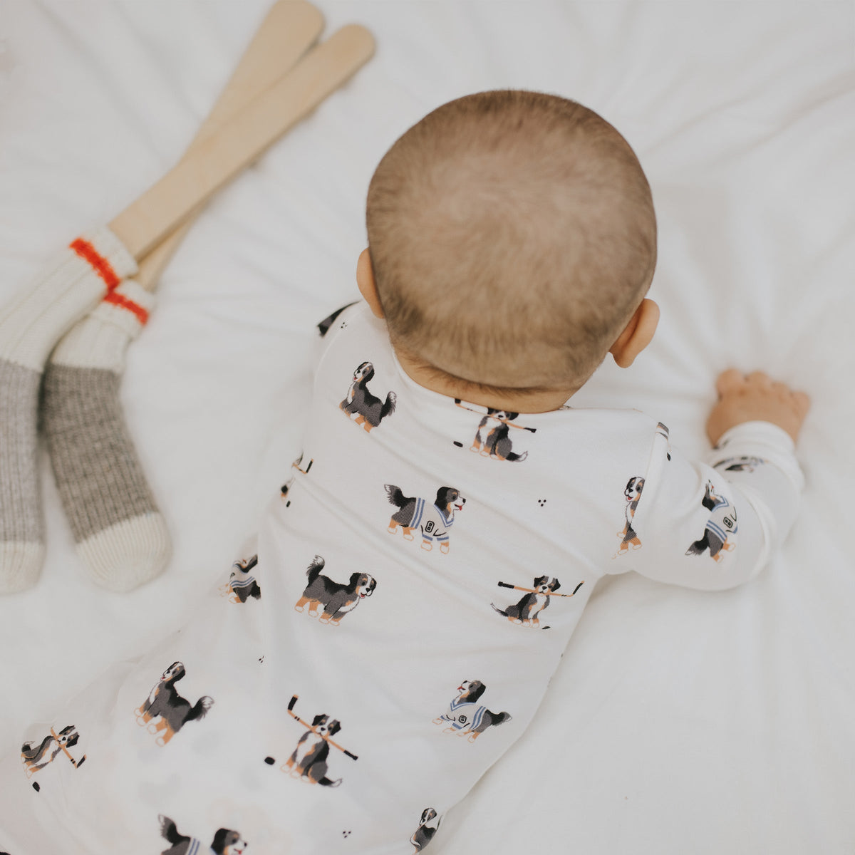 A baby wearing a white footed sleeper with an all-over dog print