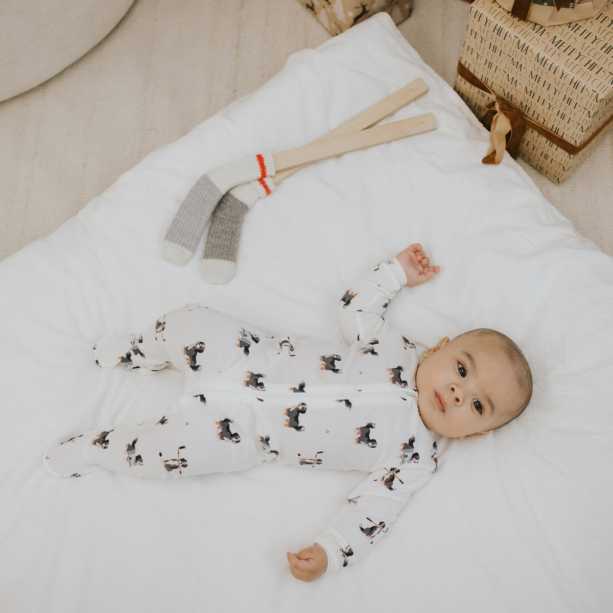 A baby wearing a white footed sleeper with an all-over dog print