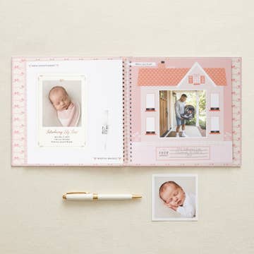 Open photo album with baby pictures on a light beige background