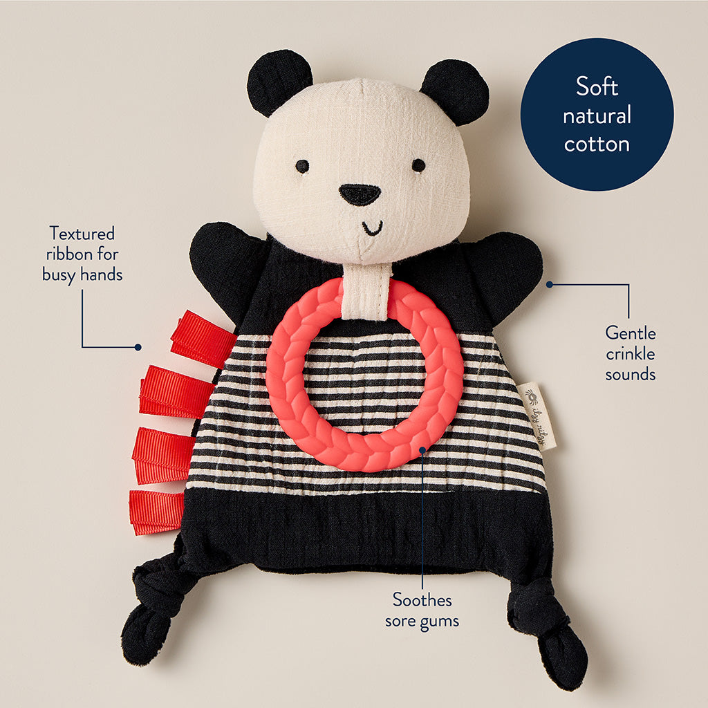 Panda-shaped toy with a textured ribbon and pink ring on a beige background