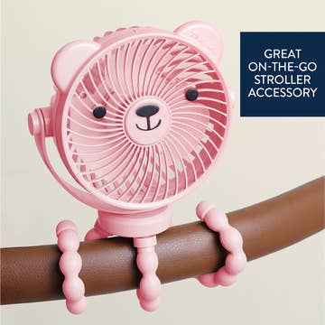 Pink lion-shaped fan attached to a stroller handle with text 'Great on-the-go stroller accessory' on a beige background.