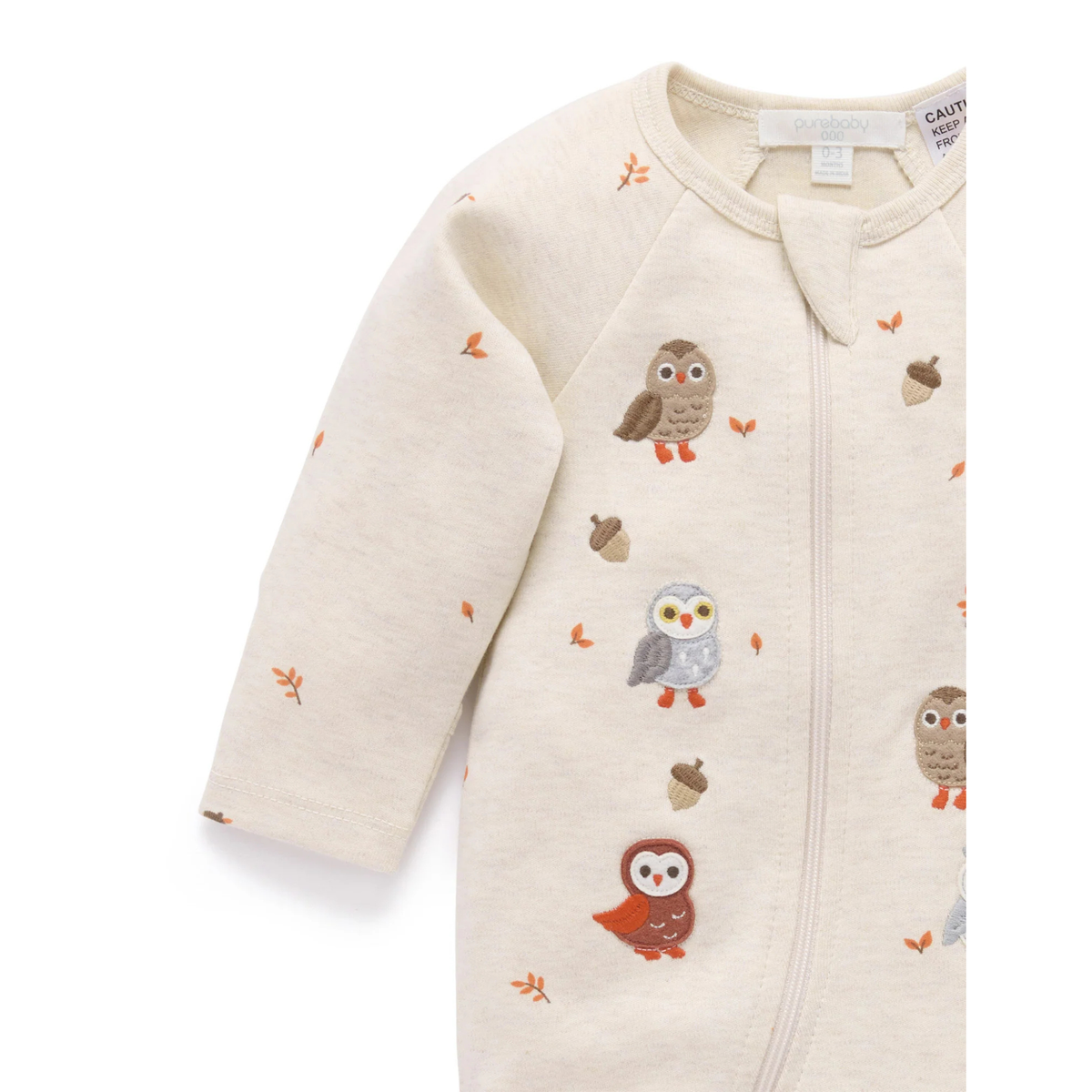 An off-white long-sleeve baby sleep sack with a front zipper, featuring a playful pattern of embroidered owls and acorns in autumn colors.