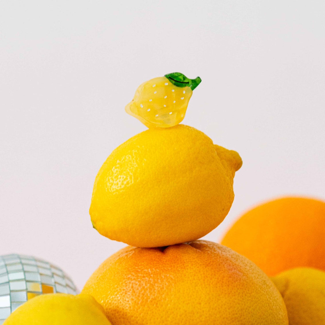 Stack of lemons and oranges with a small toy lemon on top against a light background