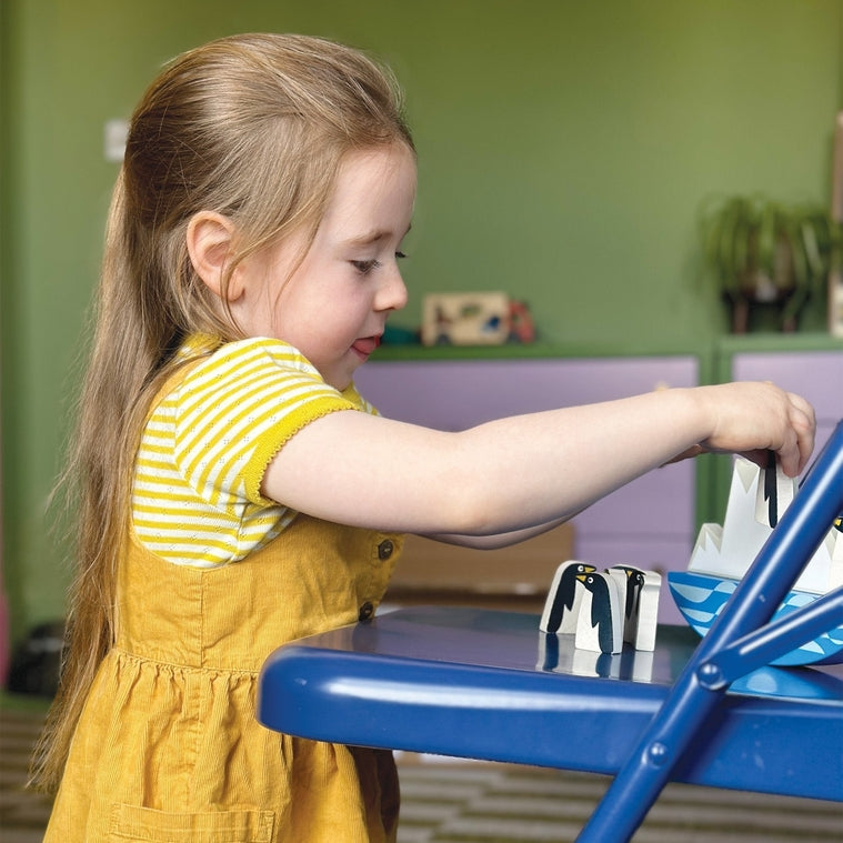 A young child with blonde hair wearing a yellow striped top is focused on playing with a toy at a table.