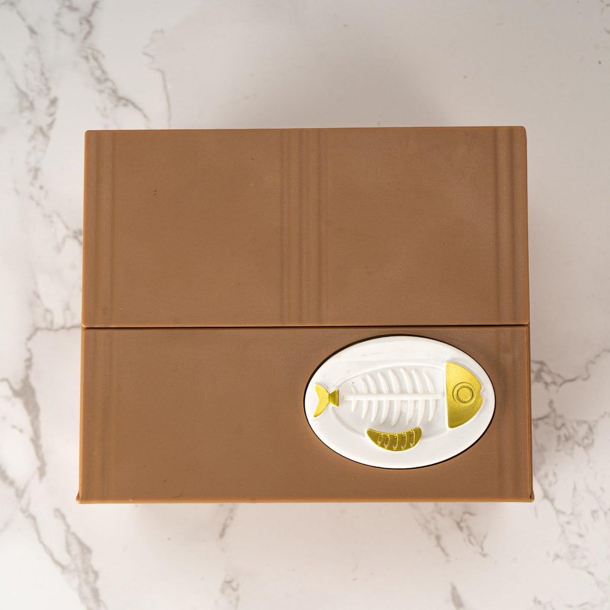 Brown box with a fish design on a marble surface
