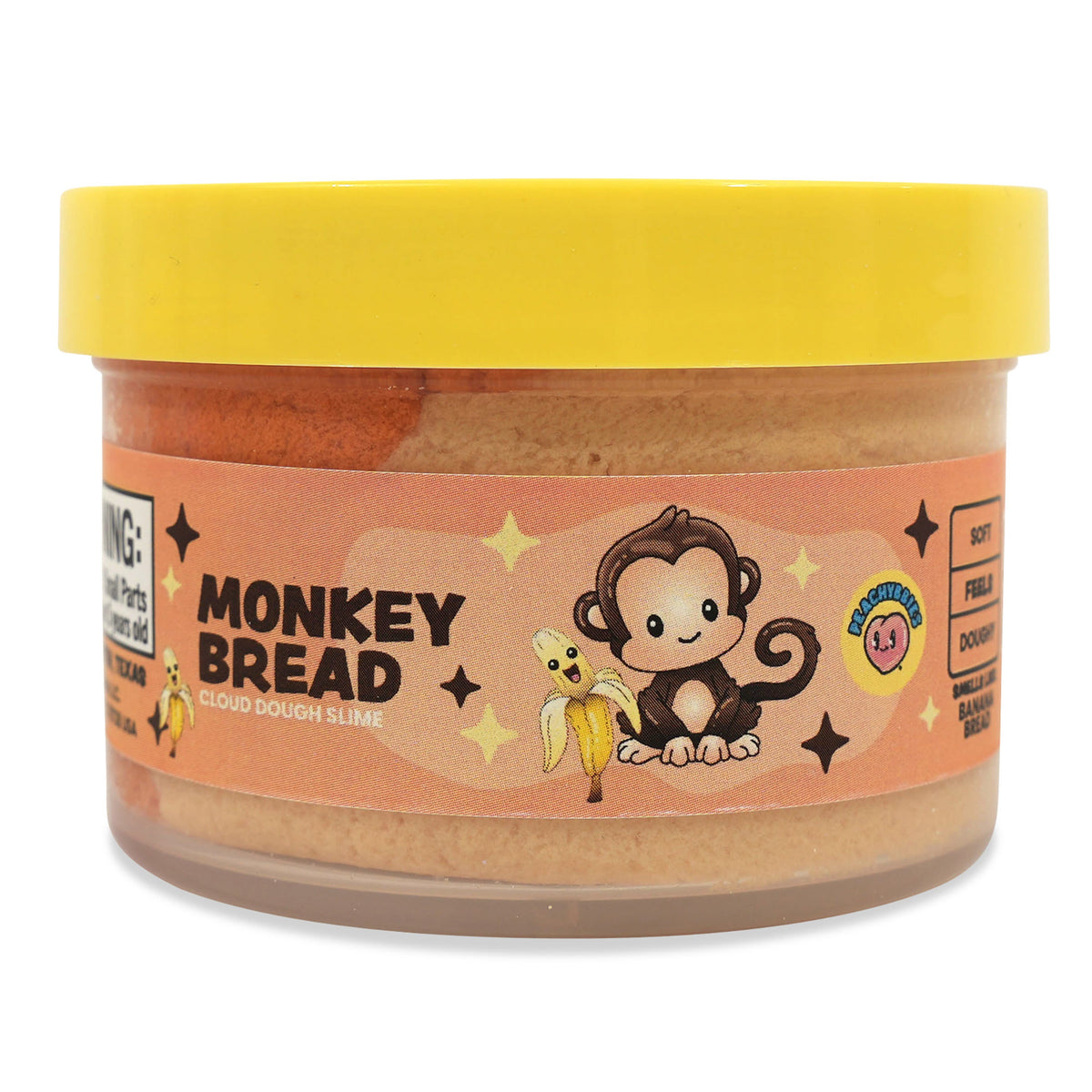A jar of Monkey Bread Peanut Butter Cookies by Monkey Wrench Cookies, featuring a bright yellow lid and a peach-colored label with a cartoon monkey holding a banana.