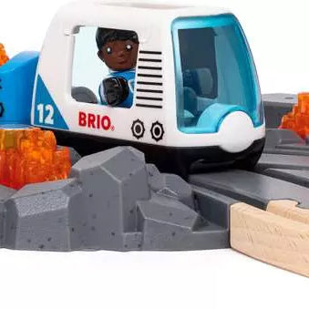 Brio World space train with a blue and white engine and cargo wagons carrying glowing orange minerals, traveling along gray rocky terrain tracks connected to wooden tracks.