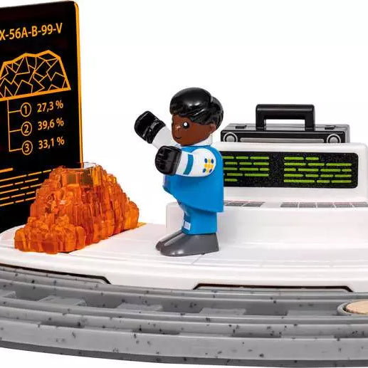 A toy construction vehicle scene with a blue and white minifigure standing beside a black control panel, an orange translucent rock, and a black display screen showing statistics, all on a white and gray vehicle base against a white background.