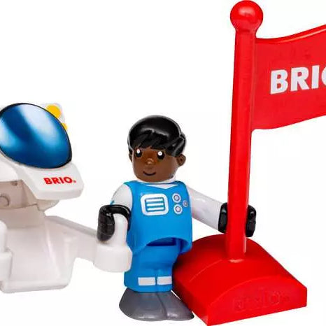Brio World astronaut figure wearing a blue and white spacesuit standing next to a white spacesuit with a blue visor, accompanied by a large red flag bearing the white Brio logo on a red base.