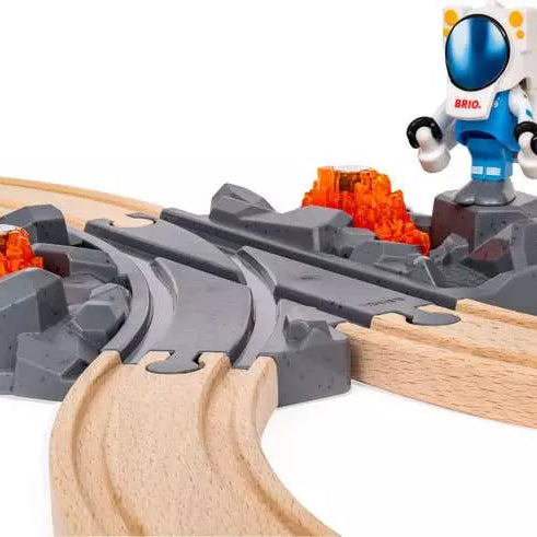 alt text for this image
Brio World astronaut figure standing next to a grey rocky terrain switch track connected to wooden tracks, with an orange translucent mineral rock in the background.