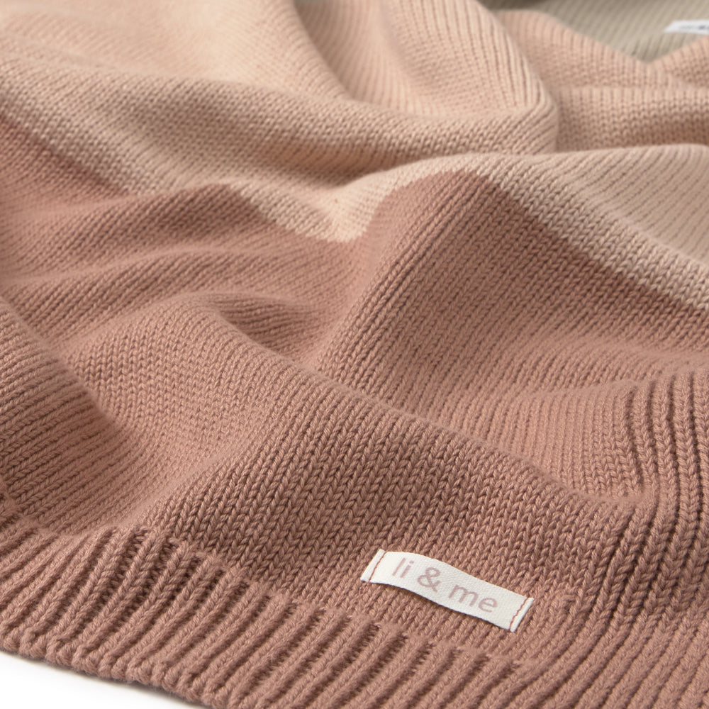 Close-up of a soft knit sweater in a dusty rose pink color, showing the ribbed texture and a small white label that reads 'i & me'.