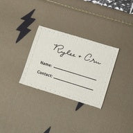 A close-up of a kraft paper envelope or gift bag with black lightning-bolt graphics, featuring a white paper insert card with printed text fields.