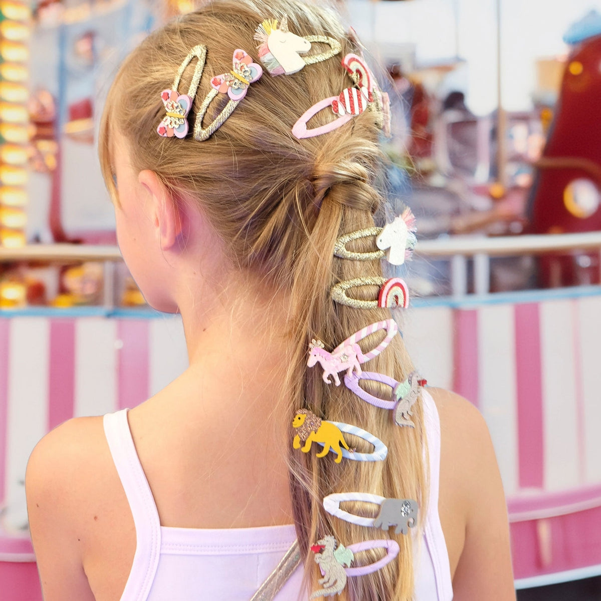 Girl with colorful hair clips in her ponytail at an amusement park.