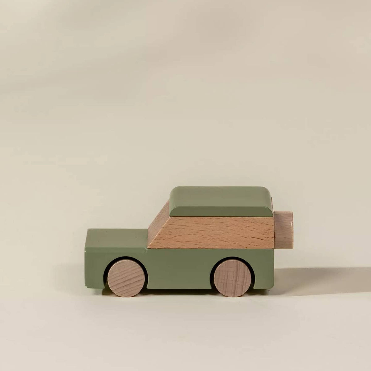 Wooden toy car with green body and brown roof on a beige background
