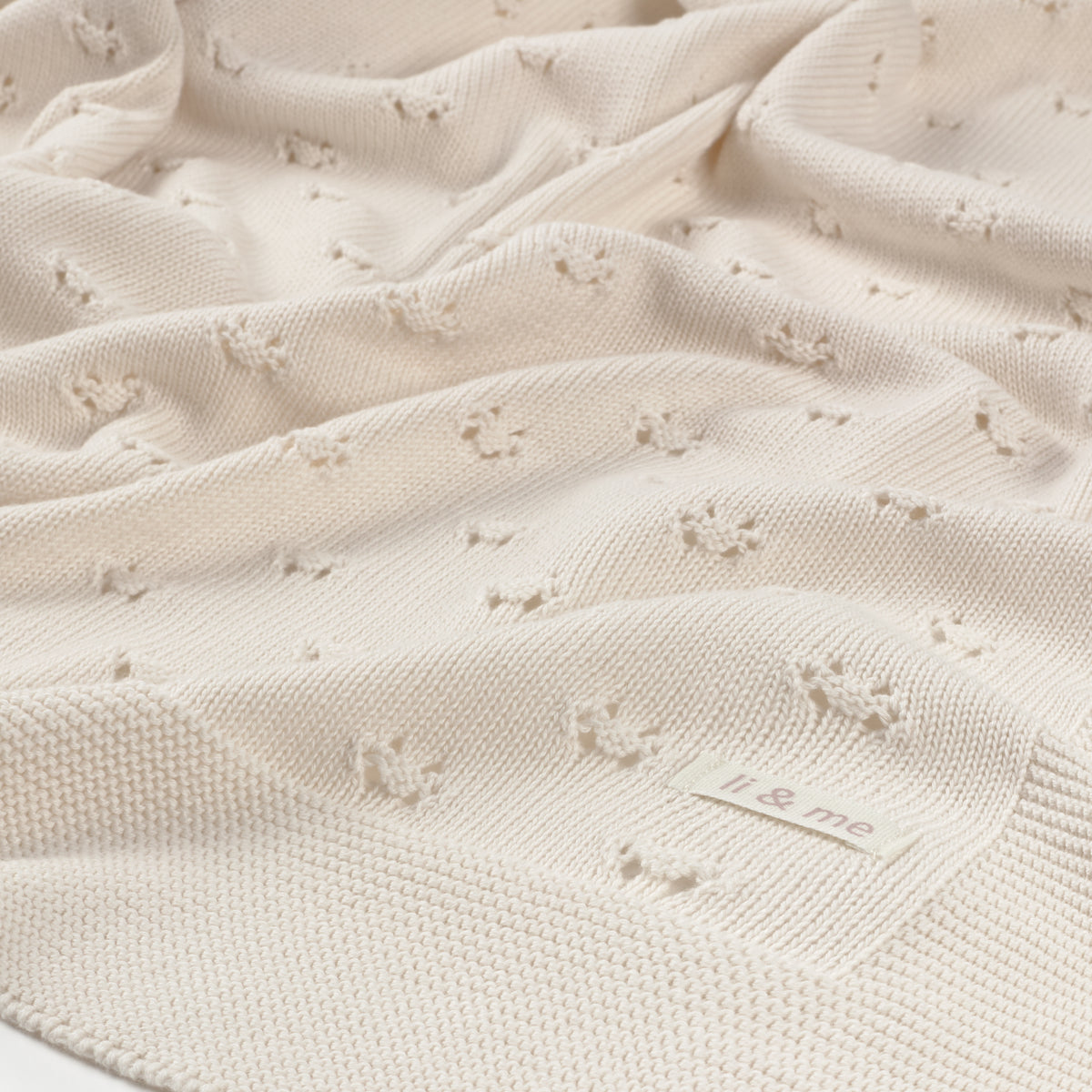 Close-up of a textured beige blanket with a brand label.