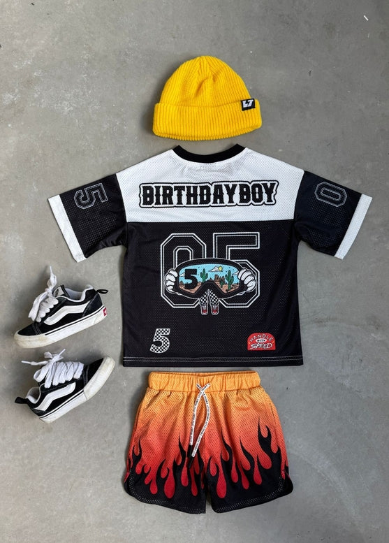 Children's birthday-themed outfit with shirt, shorts, and shoes on a neutral background