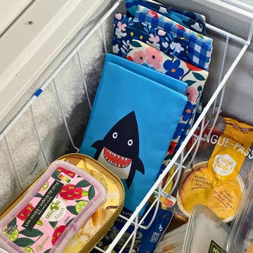 Colorful reusable bags with various designs in a shopping cart.