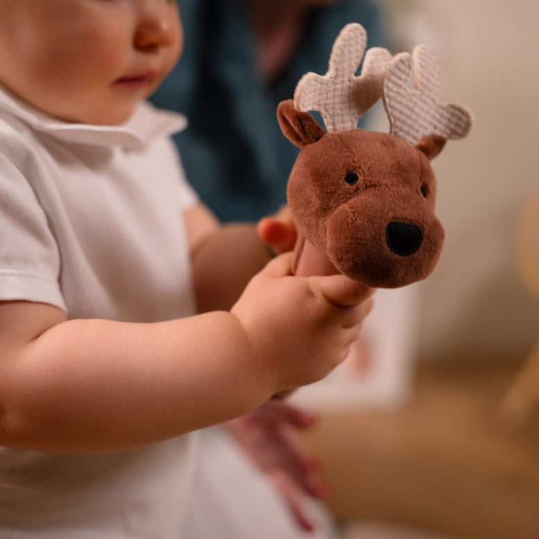 Child holding a plush reindeer toy with a blurred background