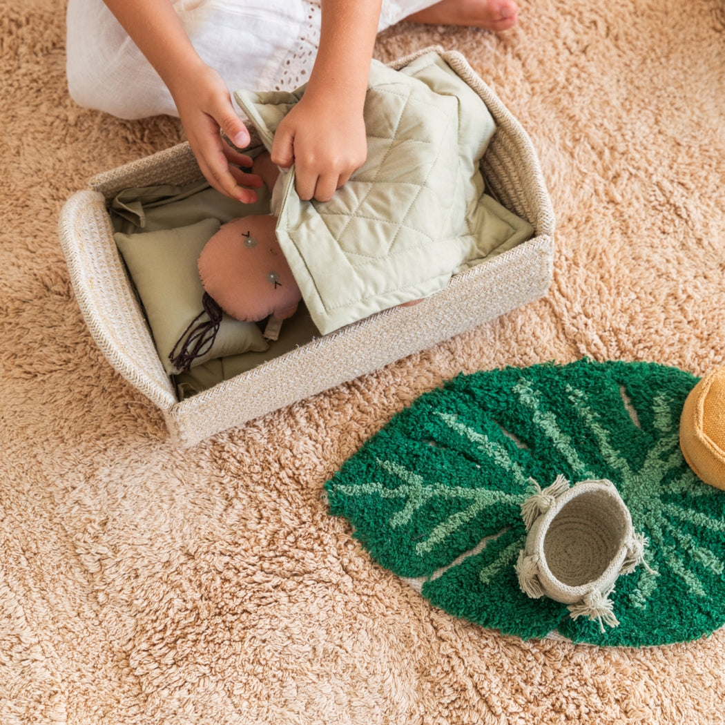 Child playing with a doll in a box on a carpeted floor