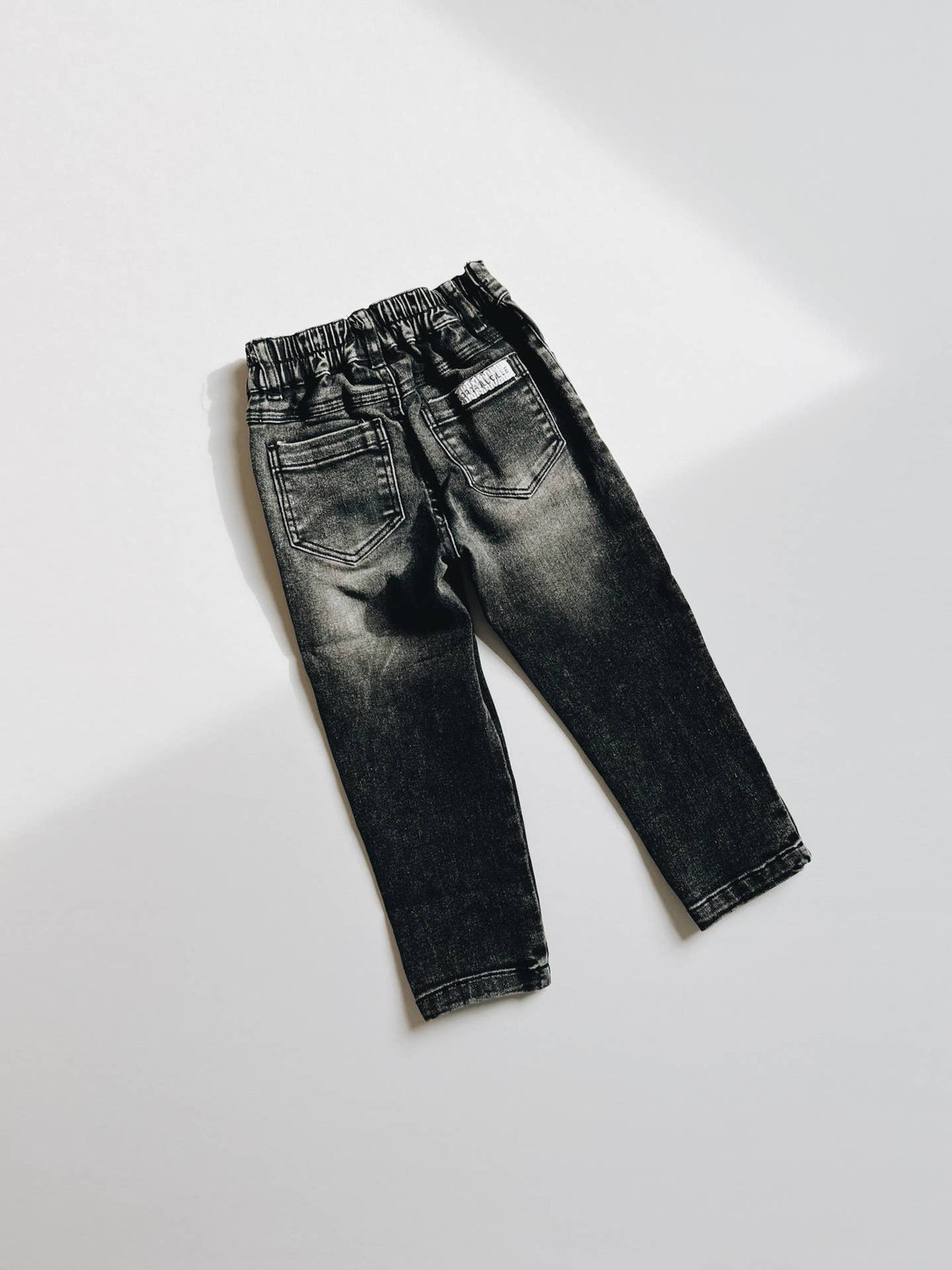 Black denim jeans on a white background