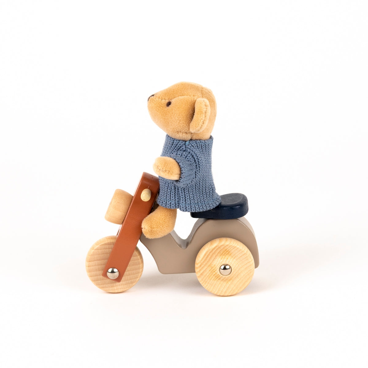 Toy bear in a sweater riding a wooden bike on a white background