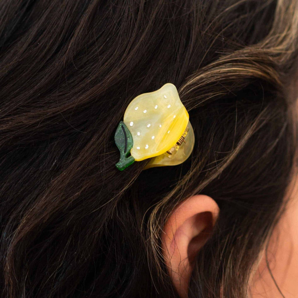 Yellow flower-shaped hair clip on dark hair