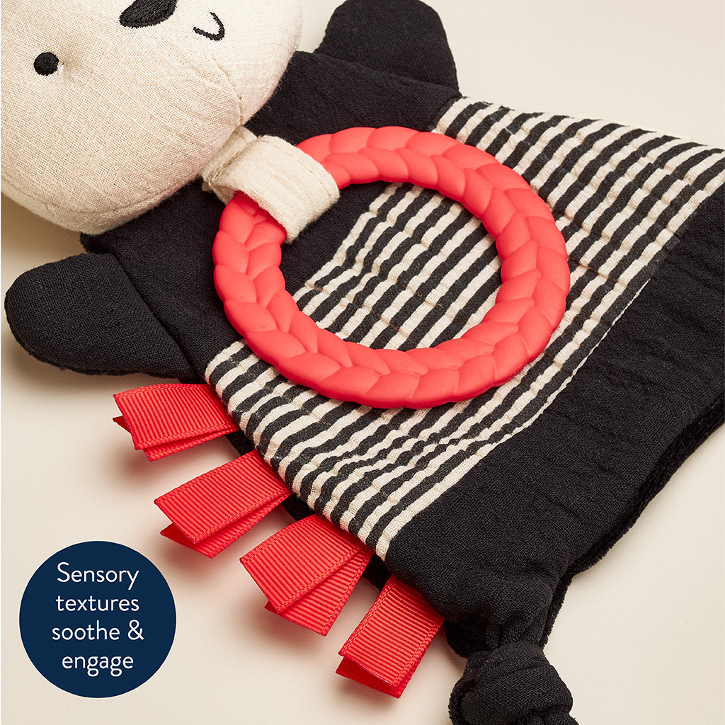 Panda-shaped toy with a red teething ring and tassels on a light background