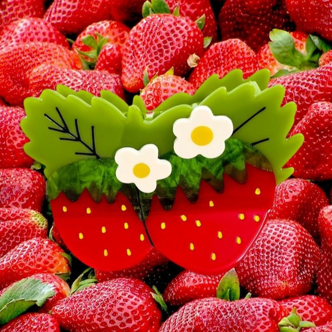 Strawberry-shaped basket with flowers surrounded by real strawberries