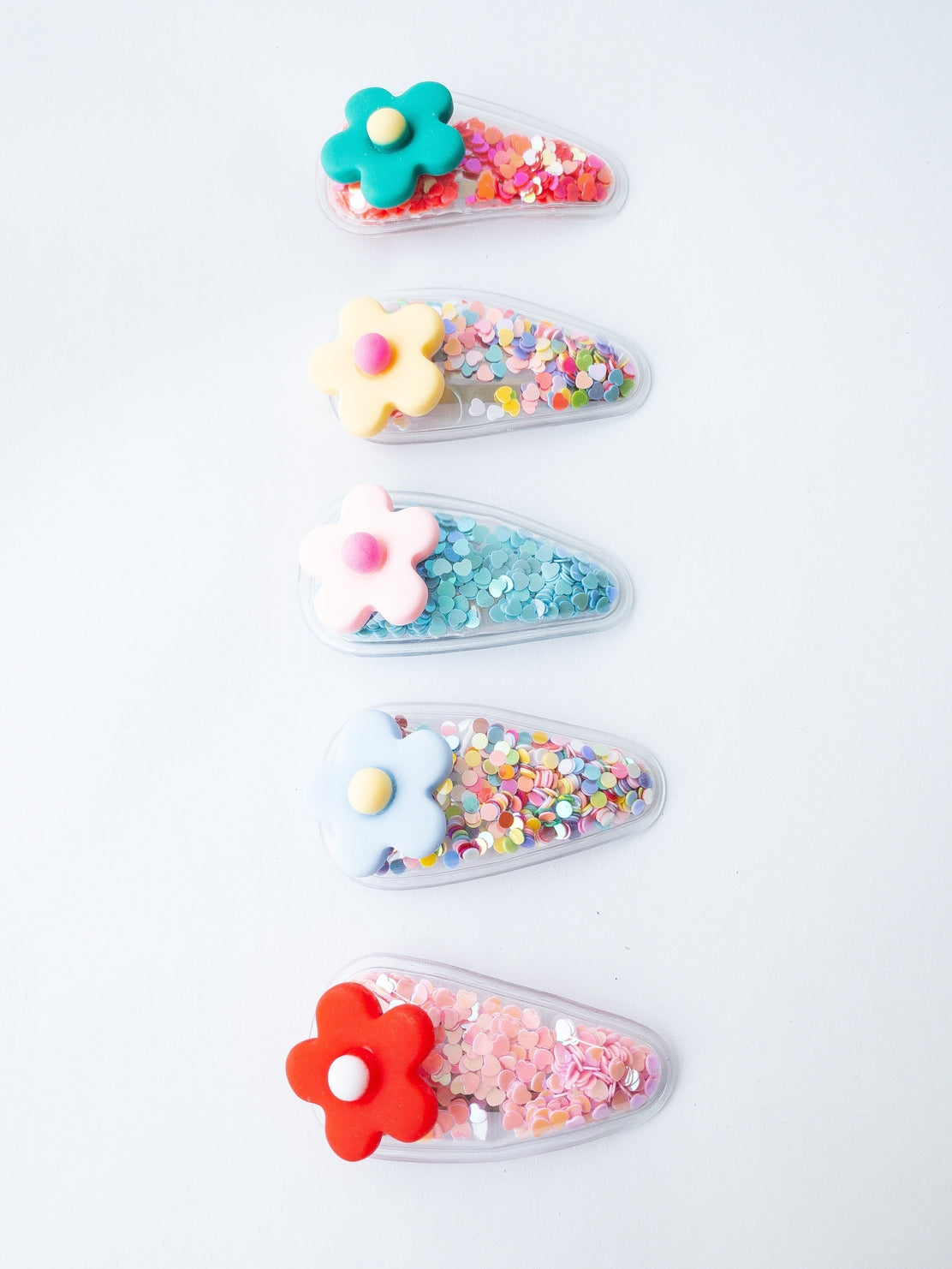 Colorful hair clips with floral designs on a light gray background